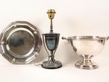 two silver dishes and a silver cup on a white surface