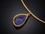 a gold necklace with a blue stone pendant on a black background