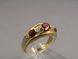 un gros plan d'une bague en or sertie de pierres rouges et de diamants