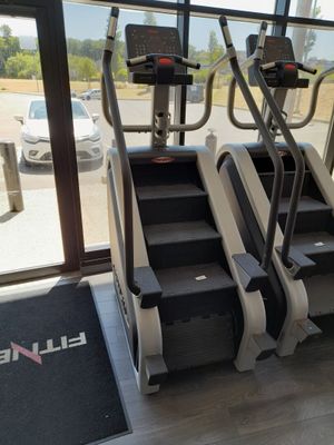 trois tapis de course dans une salle de sport donnant sur un parking