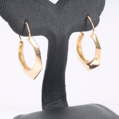 pair of gold toned hoop earrings on a black stand