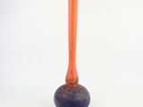un petit vase orange posé sur une table blanche