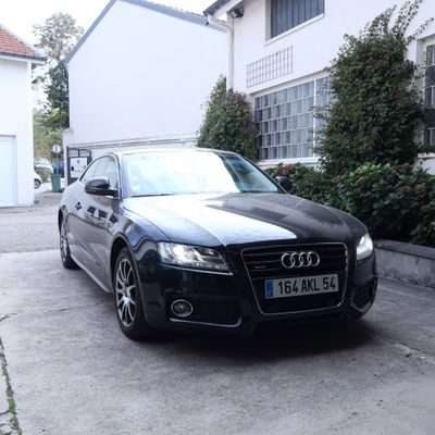 une voiture noire garée devant une maison blanche