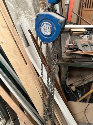 a blue crane hanging from a chain next to a pile of wood