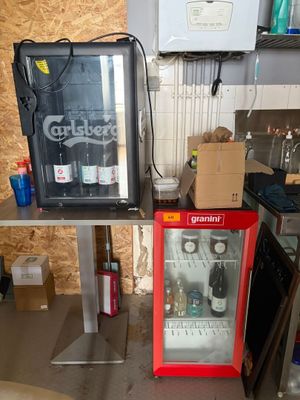 two soda coolers sitting next to each other in a room