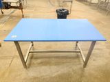 a blue table in a warehouse with chairs around it