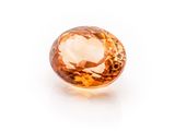 a close up of an orange sapphire stone on a white surface