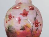 a pink vase with flowers painted on it on a white surface