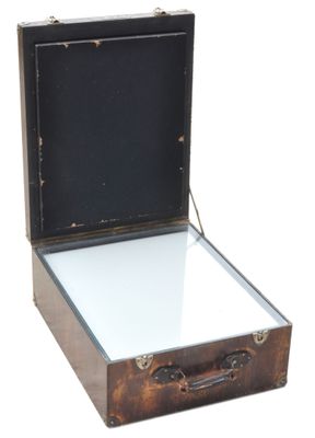 une valise contenant un miroir, posée sur une surface blanche