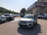 une voiture blanche garée devant un immeuble devant lequel sont garées de nombreuses voitures