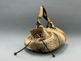 beige snake skin purse with leather handles on grey background