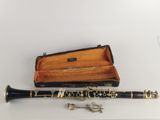 a black and gold clarinet with a case on a white surface