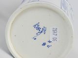 a white cup with blue writing on it sitting on a white surface