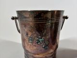 a metal bucket with a handle sitting on a table