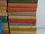 many books stacked on top of each other on a bed