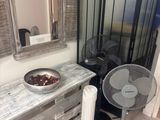 a table with a bowl of fruit on it next to a fan