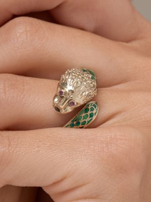 une image représentant la main d'une femme tenant une bague ornée d'un serpent