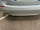 a silver car parked in a parking lot with a sticker on the back of it