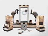 une horloge posée sur une table, à côté de deux statues d'oiseaux