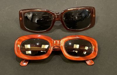 two pairs of sunglasses sitting on top of a table next to each other