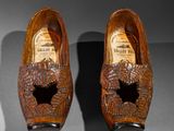 pair of carved wooden shoes with holes in them on a table