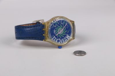 montre-bracelet avec un bracelet en cuir bleu, un boîtier doré et une pièce de monnaie