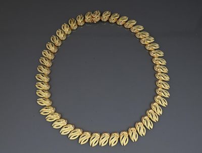 a gold necklace with leaves on a grey background