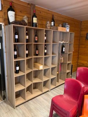 Des bouteilles de vin sont rangées sur des étagères dans une cave à vin où se trouvent des chaises rouges