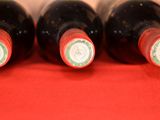 four bottles of wine are lined up on a red cloth