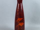 un vase rouge posé sur une table près d'un mur blanc