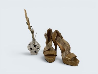 a pair of high heeled shoes next to a vase with a flower