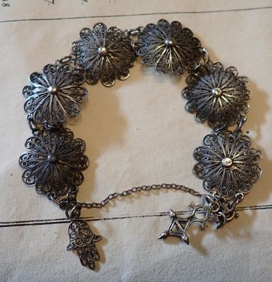 bracelet plaqué argent orné de breloques, posé sur un morceau de papier