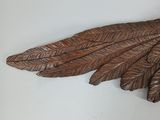 a wooden sculpture of a bird with feathers on it ' s wings