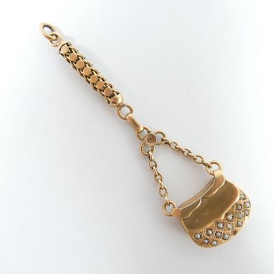 une image représentant une chaîne en or à laquelle est suspendu un pendentif en forme de sac à main