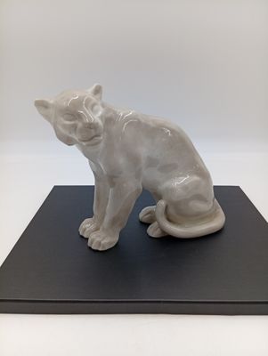 statue d'un chat assis sur un socle noir, sur fond blanc