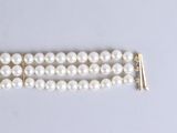 two rows of white pearls with gold clasps on a white surface