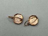 a pair of gold earrings on a gray surface