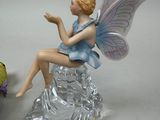 a figurine of a fairy sitting on a rock next to a bird