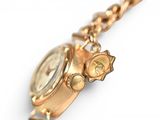 a gold watch with a chain around it on a white surface