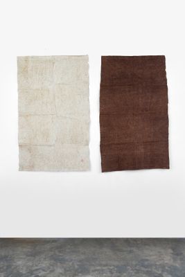 trois morceaux de tissu marron, blanc et marron accrochés à un mur