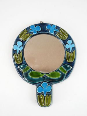 blue and green mirror with flowers and leaves on it on a white surface