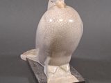 a white bird statue sitting on top of a black base
