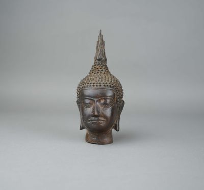 une vieille tête de Bouddha en bronze sur fond blanc