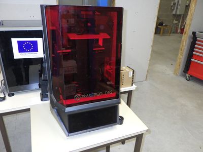 une grande imprimante 3D rouge posée sur une table blanche