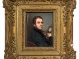 portrait of a man in a black coat holding a brush and a mirror