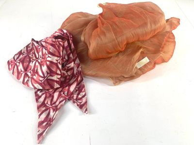 a red and white scarf and a pink and white scarf on a white surface