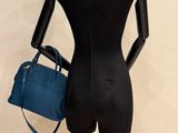 mannequin holding a blue handbag on a mannequin stand