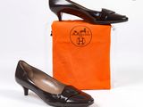 des chaussures en cuir noir, accompagnées d'un petit sac orange et d'une paire de talons hauts