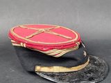 un chapeau rouge orné d'une croix sur fond noir