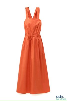une robe orange à bretelles suspendue à un cintre sur fond blanc